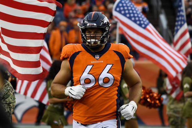 Jared Veldheer running onto the field in a Denver Broncos uniform with American flags behind him